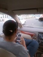 a man with a phone sits at the wheel of a car on the road