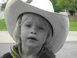 Black and white photo baby in a cowboy hat at colorful background with beautiful nature