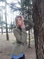 girl smokes a cigarette near a tree