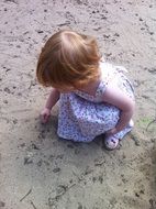 little blond girl playing with sand