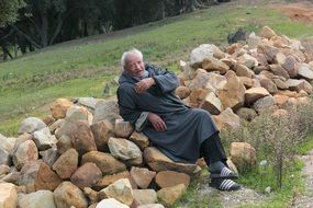 tunisian senior man resting on pile of stones, tunisia