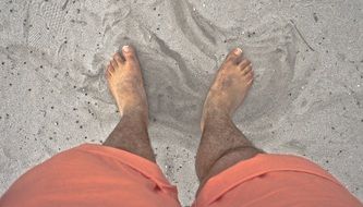 barefoot man stands on sand