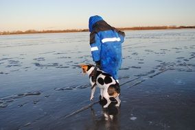 man and dog on the ice on the lake