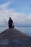 A man walks along the pier near the sea