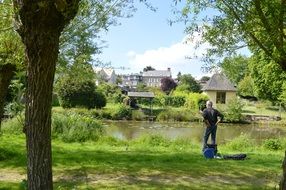 fisherman stands on a green bank near the river