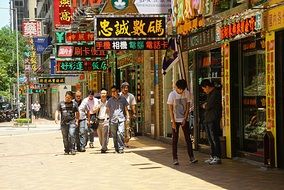 people walk down the street near shops