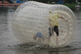 people in a transparent wheel on the water