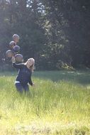 girl with balloons in meadow