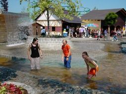 children play in the fountain on a summer day