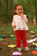 innocent girl among colorful papers in the garden