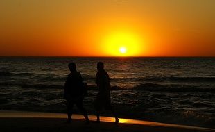 people walking along the beach of the baltic sea at sunset