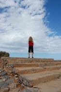 child girl standing on top of stone stepway at sky