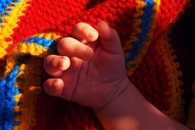 hand of a sleeping child on a wicker rug