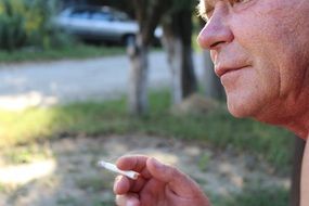 old man smoking cigarette in yard