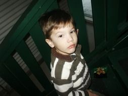 a boy in a striped sweater climbs the stairs