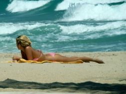 girl in pink swimsuit sunbathing on the beach
