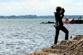 man with a camera on the stairs by the sea