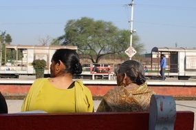 two old women on bench at railway station, india, punjab
