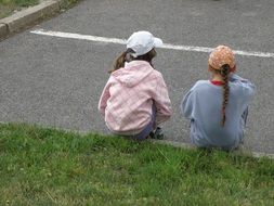 little girls sit on green grass