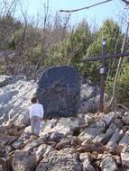 man near a big cross on a rock