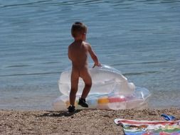 baby with a rubber ring on the beach