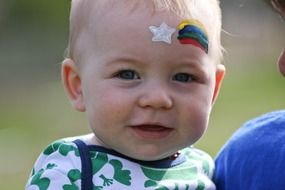 baby boy face with rainbow painting on forehead