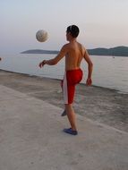 athlete with ball on the promenade at dusk