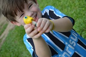 boy playing with a water gun on green grass