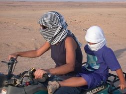 mother and baby ride a desert quad bike