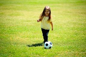 child girl playing soccer on lawn