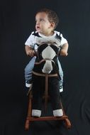 happy baby on a wooden horse on photoshoot