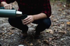 man pours tea from a thermos