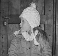 child girl in white hat at wooden doot