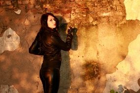 Girl with black hair wearing a leather jacket against the background of the wall
