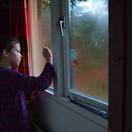 boy draws on a sweaty window during rain