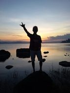 silhouette of a person by the lake at sunset