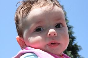 adorable baby against the sky on a sunny day