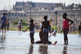 dark skin childreen playing in water on street