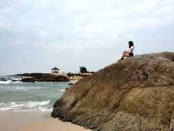 girl sitting on a stone on the beach