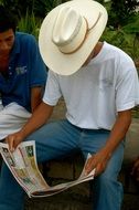 man in a cowboy hat with a newspaper