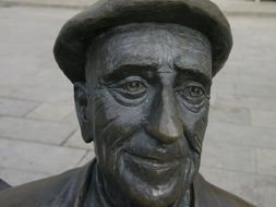 smiling mature man in cap, bronze sculpture