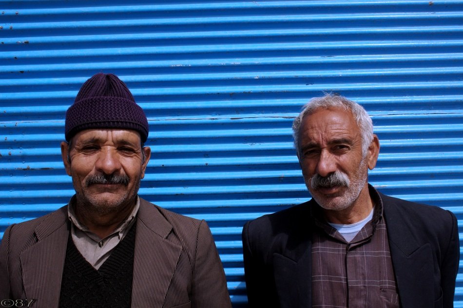 Iranian men stand near the blue wall