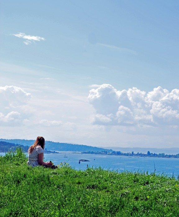 girl sitting on the green grass on the background of the sea