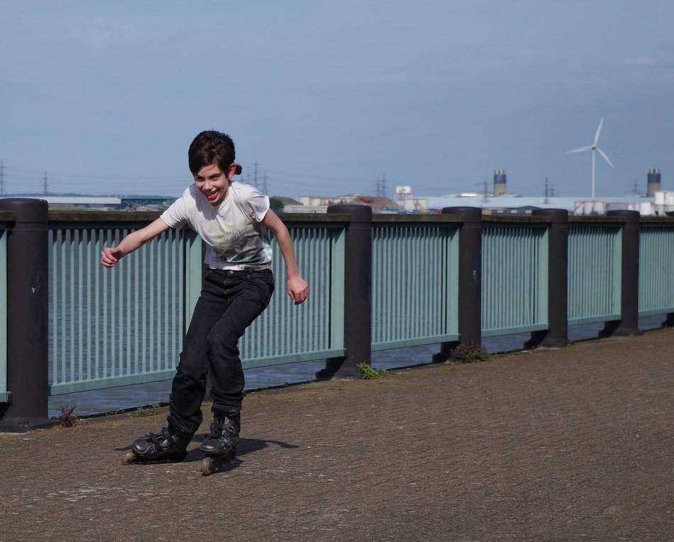 fun teen boy on rollerblades on bridge