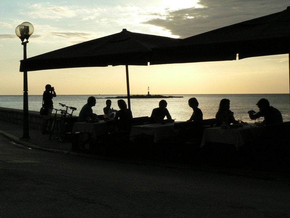 Silhouettes of people at dinner on the coast
