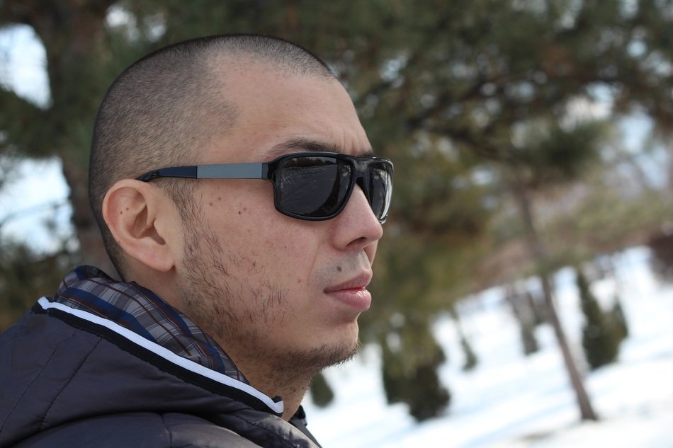 short-haired man in sunglasses against the background of a winter landscape