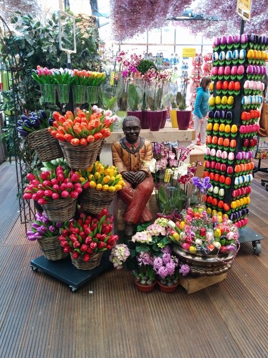 dark skin man statue among tulips in flower shop