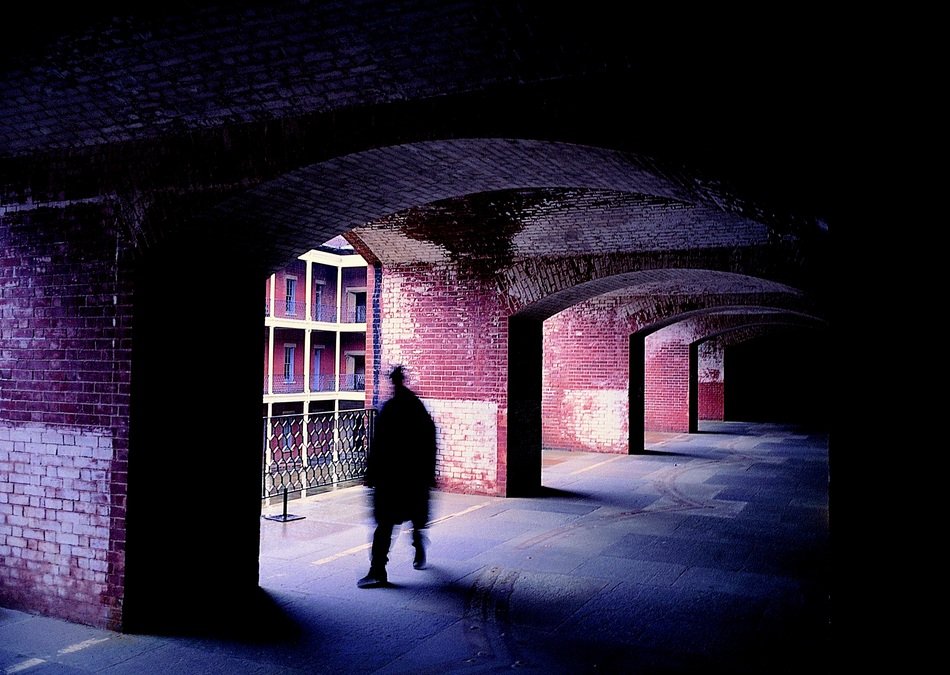 person in the shadow of the corridors with light outside
