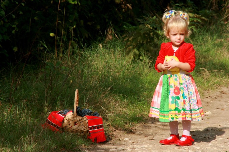 baby girl in a dress on a background basket with autumn fruit