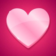 Glossy plastic heart on pink background